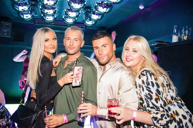 Four friends pose with drinks at OMG Bristol Bar