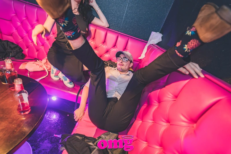 a man raises his legs in the air in a booth at OMG Bristol Bar