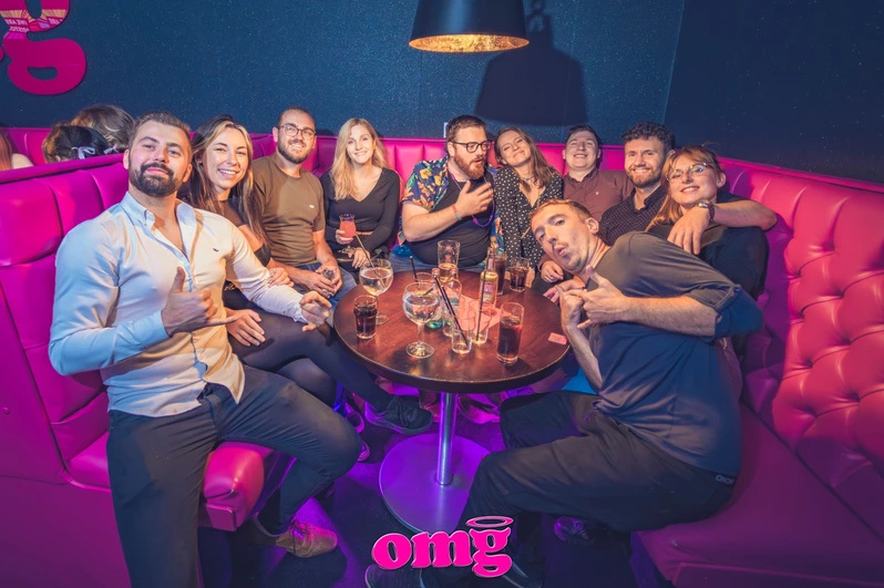 a group of friends sit around a booth with drinks at OMG Bristol Bar