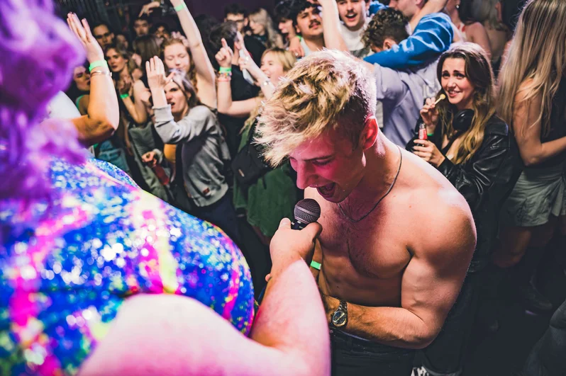 Drag queen holds a mic up to a young man at OMG Bristol Club